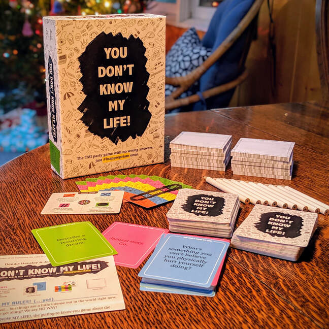 Question cards, pencils, answer sheets, instructions, and original packaging of the You Don't Know My Life adult card game spread out on a kitchen table